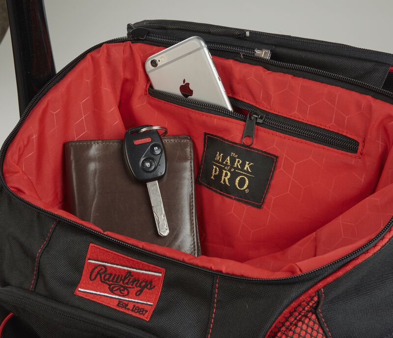 Top compartment of a scarlet/black R600 Players team bag with a phone, wallet and keys and “The Mark of a Pro” patch