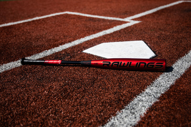 A red/black Rawlings BBCOR Quatro Pro lying next to home plate - SKU: BBZQ3