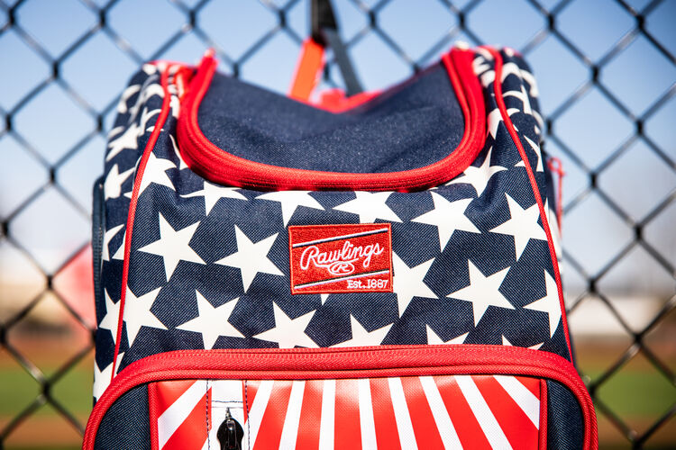 The red Rawlings patch on a USA Rawlings Legion backpack hanging on a fence - SKU: LEGION-USA