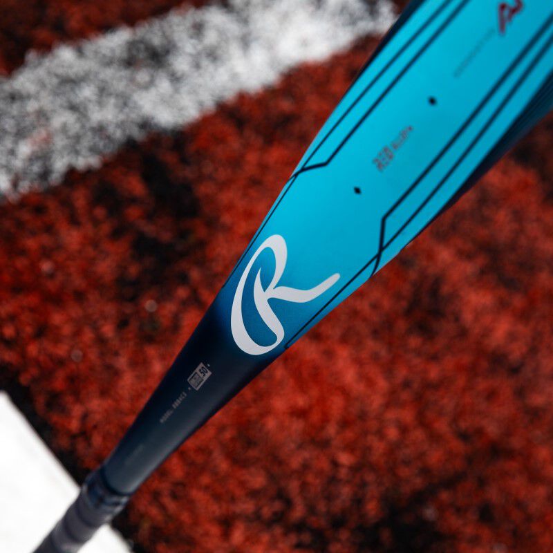 White "R" Rawlings logo on a blue Clout AI BBCOR bat with a field in the background