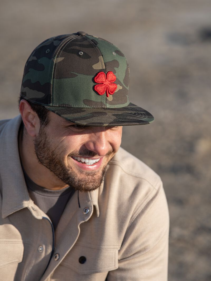 A guy wearing a camo Rawlings Black Clover Game Day Camo fitted hat - SKU: BCRGDC0081
