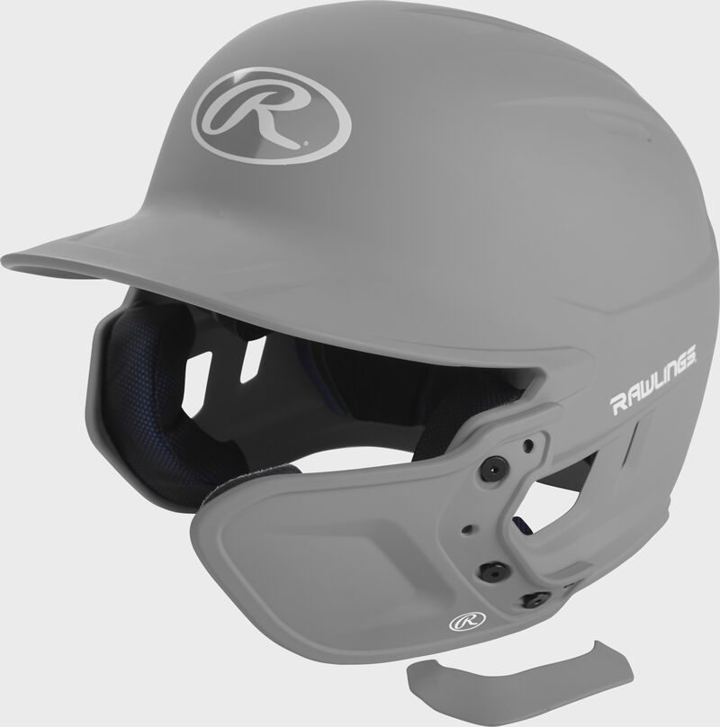 A silver MEXTR attached to a Mach batting helmet with the removable TPU piece off to show the hardware