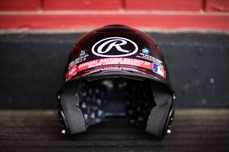 Front of a Rawlings Coolflo baseball helmet sitting on a bench in a dugout - SKU: RCFH